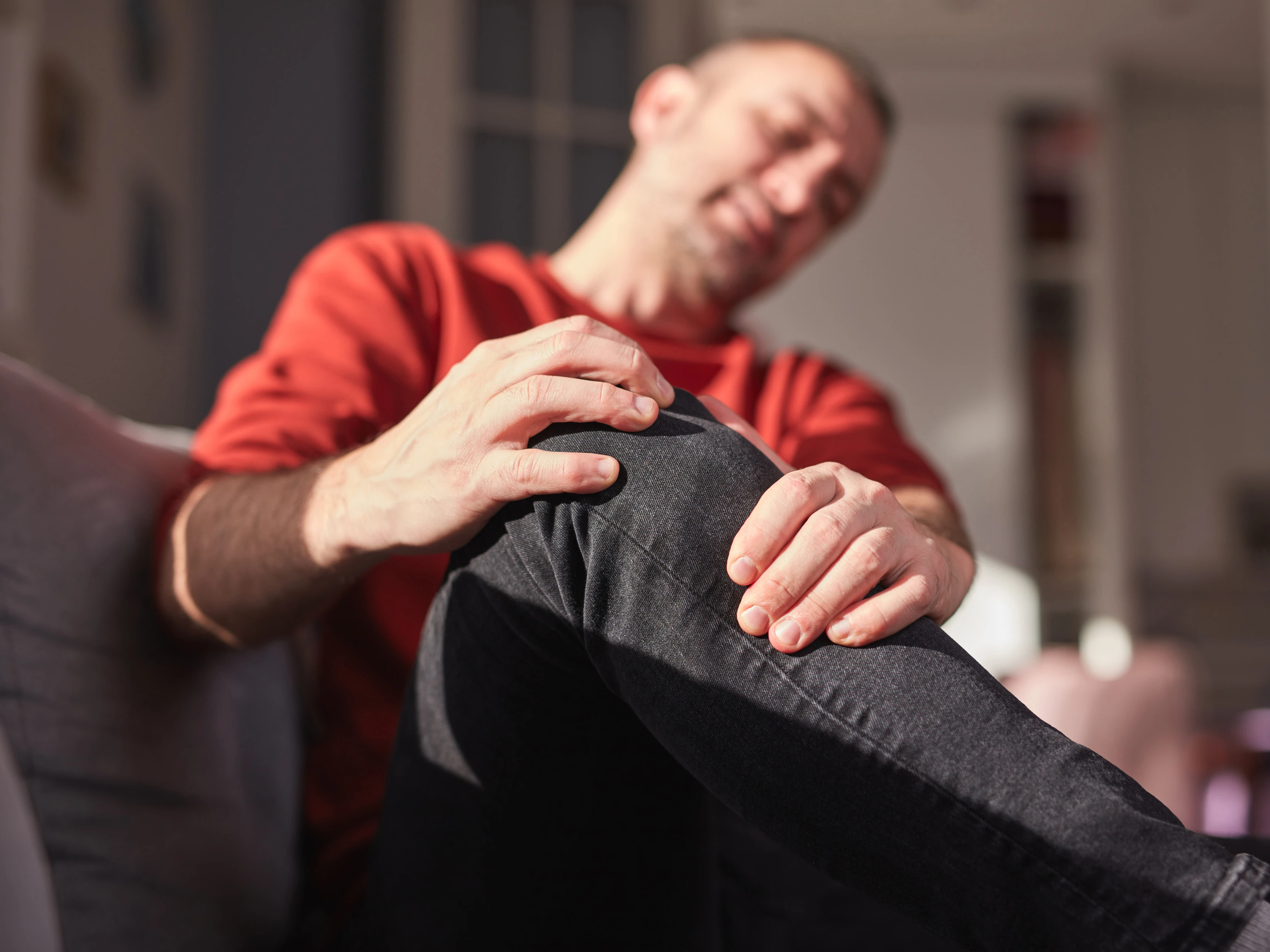 Mann umfasst mit Händen sein Knie