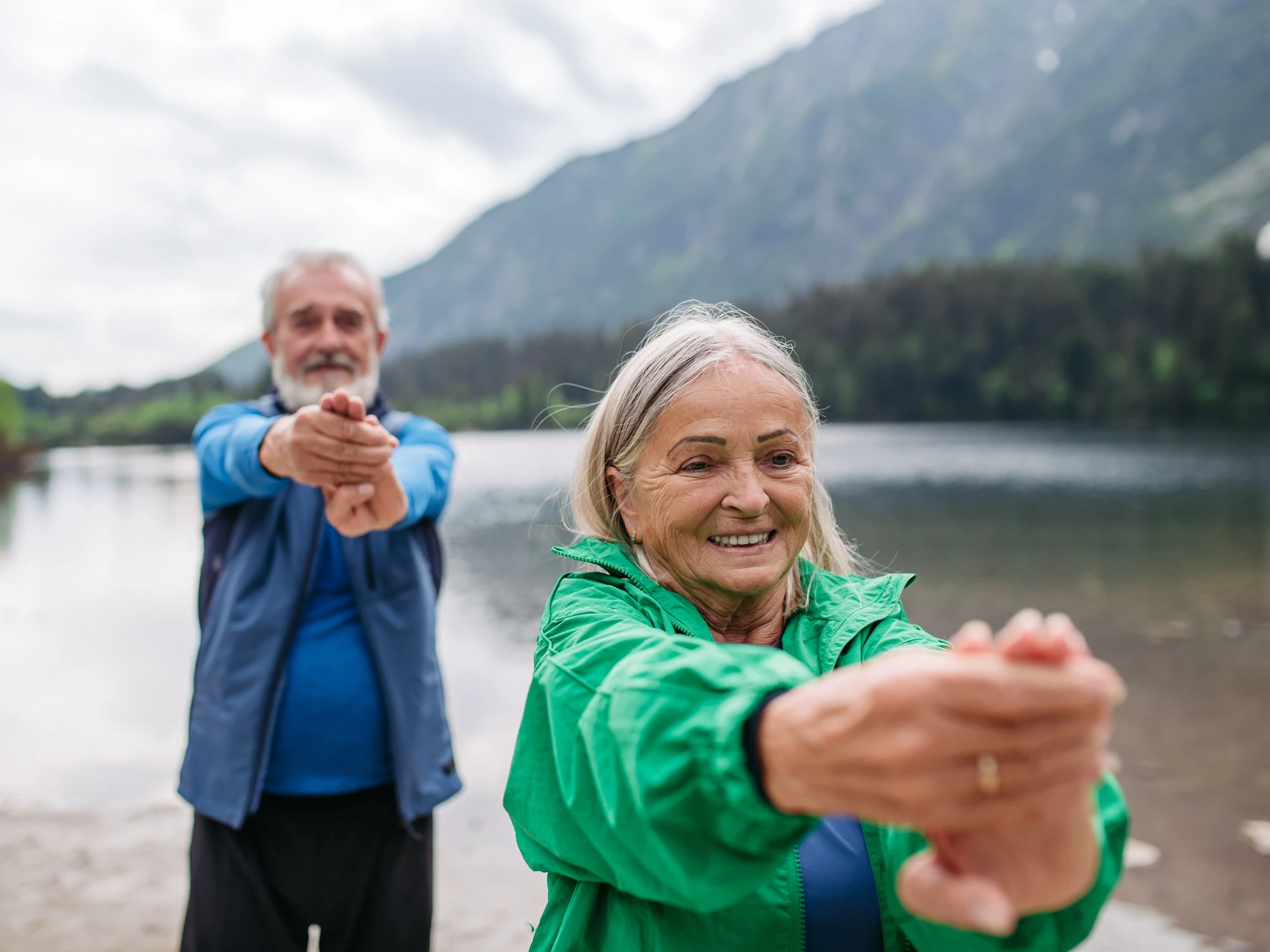Zwei Menschen dehnen ihre Handgelenke in der Natur., um Osteoporose vorzubeugen. 
