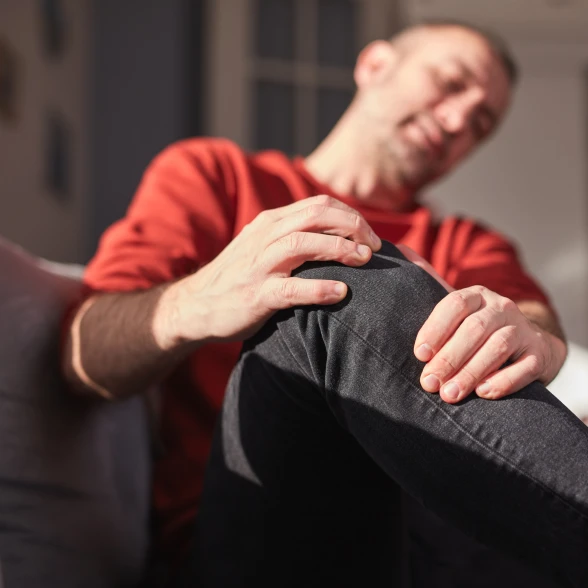 Dolori articolari al ginocchio Un uomo si tocca il ginocchio che gli fa male