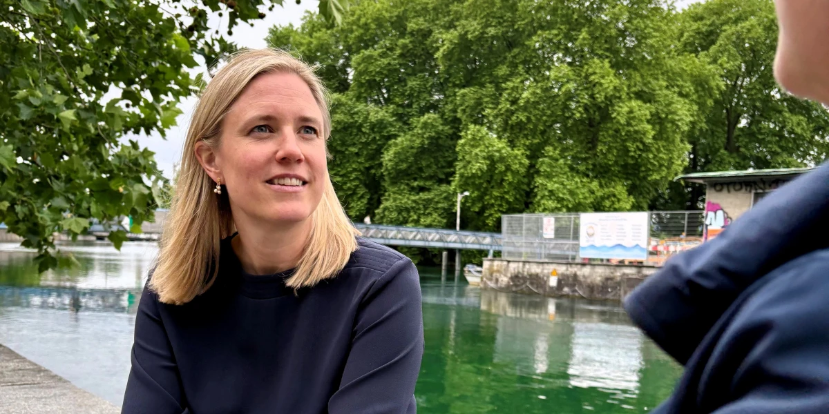 Due donne stanno chiacchierando sedute su un muretto in riva al fiume.