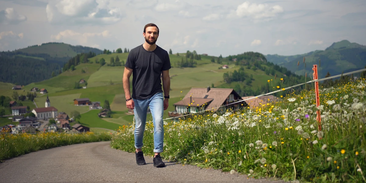 Un uomo cammina lungo una stradina di campagna in salita.