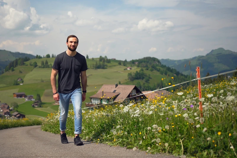Roman Sifrig durante le riprese della campagna “Io e i miei reumatismi” Un uomo cammina lungo una strada di campagna in salita